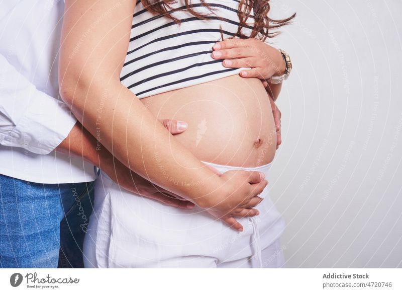 Anonymous husband touching belly of pregnant woman couple touch belly pregnancy await expect childbearing prenatal love caress maternal unborn tummy studio wife