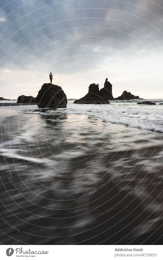 Distant traveler on rocky formation in sea water nature island trip adventure waterfront seashore environment spain canary tenerife summer landscape location