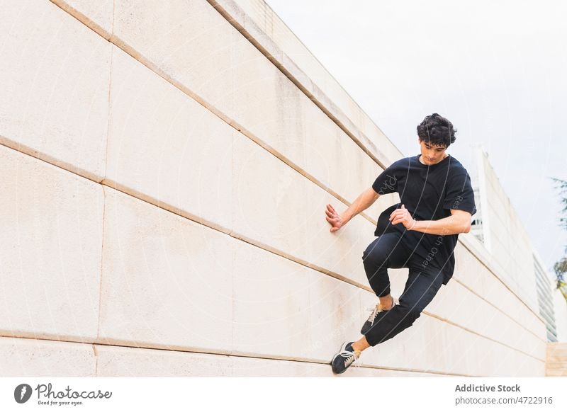 Sportive guy doing parkour stunt on wall on street man jump building above ground acrobatic energy perform male trick activity urban action active adrenalin