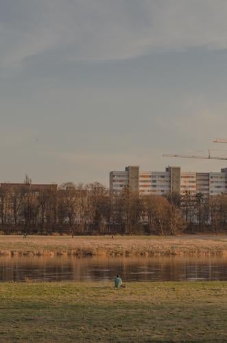 Person sitting alone on the banks of the Elbe in Dresden Elbufer Lonely Loneliness City trip Vacation & Travel Being alone depression person Sit River bank Town