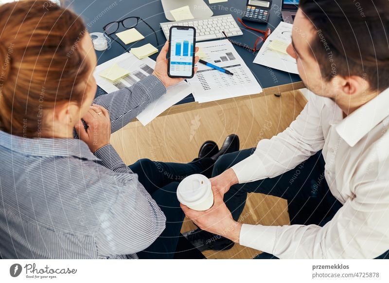 Business colleagues discussing financial data working together in office. People entrepreneurs working with charts and tables on computer and smartphone. Two people working together