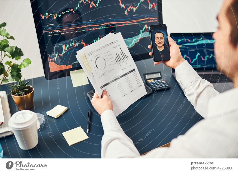 Businessman trading stocks online. Stock investor discussing numbers at graphs while video conversation with his colleague. Business team planning and analyzing stock market graphs. Business man investing stock online