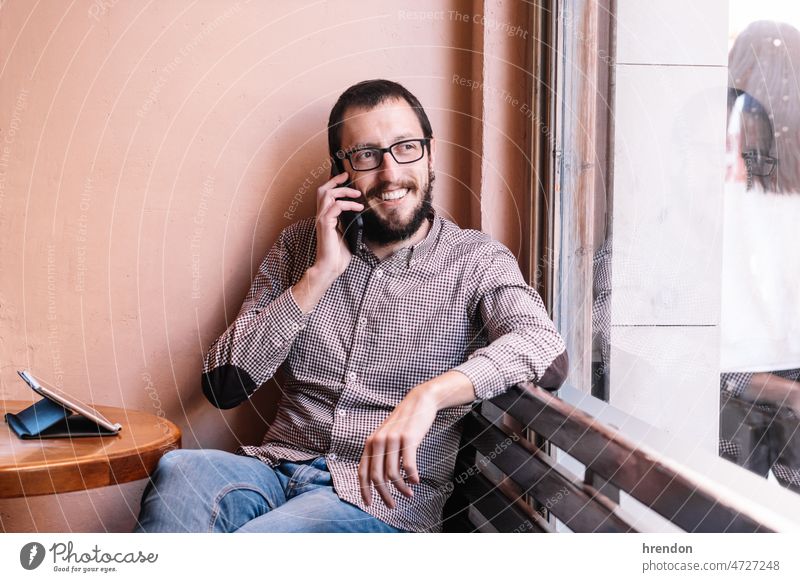 Young caucasian man smiling happy talking on the smartphone mobile phone communication male indoor technology business smile businessman lifestyle conversation