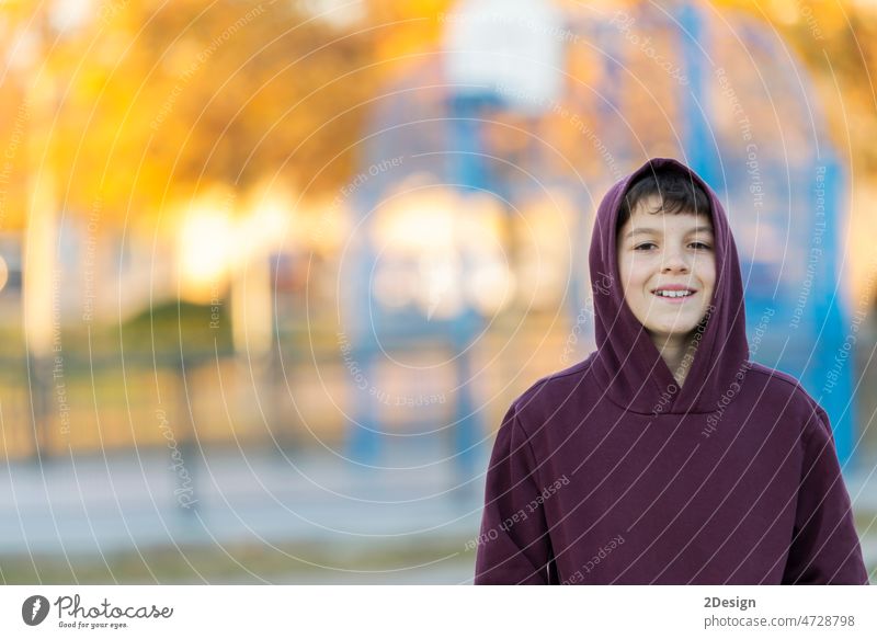 Smiling teen boy 14-16 year old wearing hoodie outdoors. Looking at camera. Teenager hood. teenage person male face portrait young children youth caucasian