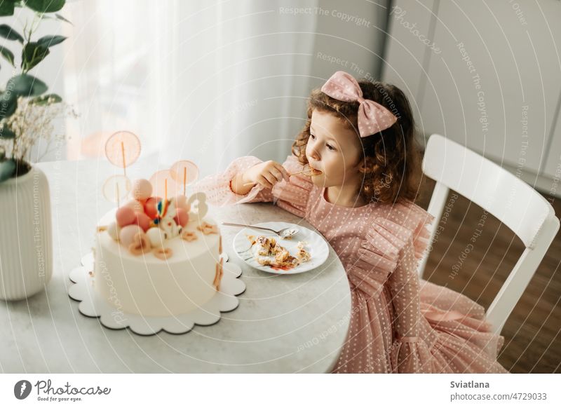 Cute little girl eats a birthday cake with a spoon on her birthday child pretty home happy kid fun sweet food dessert beautiful party portrait childhood funny