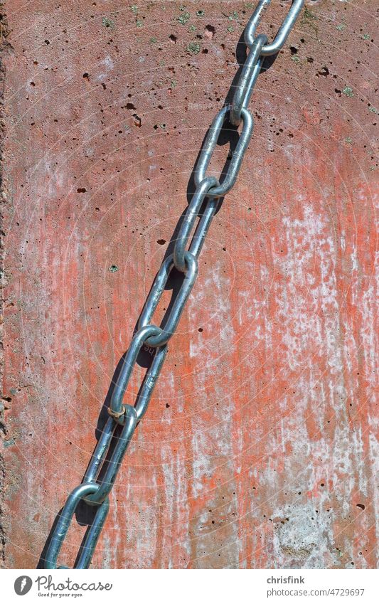 Chain of metal links against red background member Chain link Wall (barrier) Concrete Wall (building) Hold Strength Stability Rust Attachment Metal Iron Steel