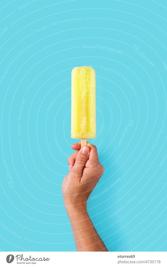 Hand holding a lemon popsicle blue cold colorful cool cream dessert flavor food fresh frosty frozen fruit hand homemade ice ice cream icecream iced juice lolly