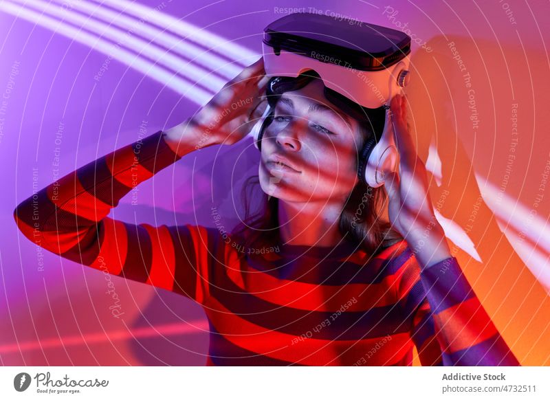 Woman in modern VR headset woman vr virtual reality light cyberspace future interactive technology explore goggles futuristic studio simulate innovation