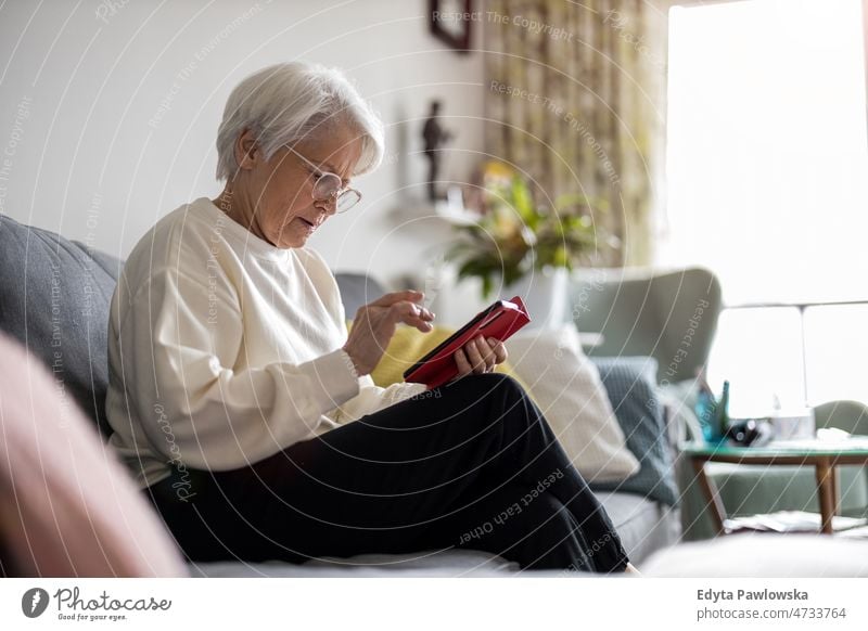 Senior woman using mobile phone at home glasses eyeglasses spectacles alone domestic life elderly female grandma grandmother grey hair house indoors lifestyle