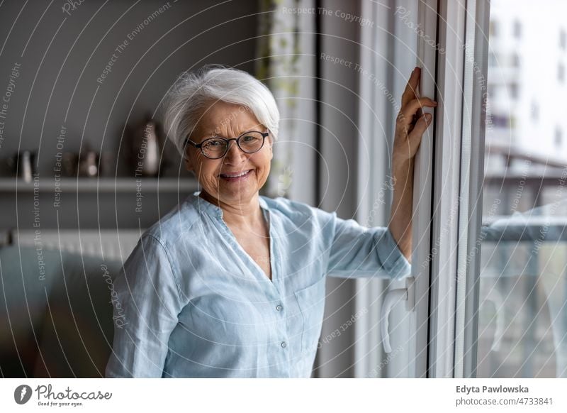 Portrait of smiling senior woman at home glasses eyeglasses spectacles alone domestic life elderly female grandma grandmother grey hair house indoors lifestyle