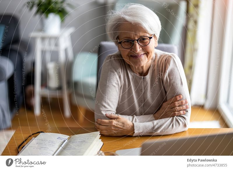 Portrait of smiling senior woman at home glasses eyeglasses spectacles alone domestic life elderly female grandma grandmother grey hair house indoors lifestyle