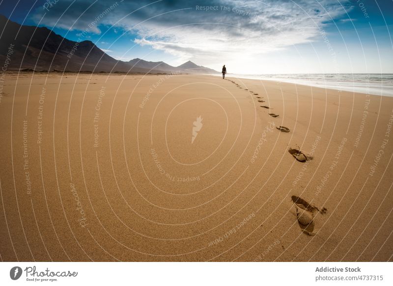 Person walking on sandy shore surrounded by hills traveler beach freedom footprint coast trip sea vacation harmony silhouette seashore journey coastline nature