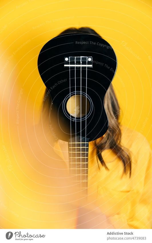 Woman covering face with acoustic ukulele in studio woman musician instrument cover face hide style bright female model artist studio shot hobby colorful