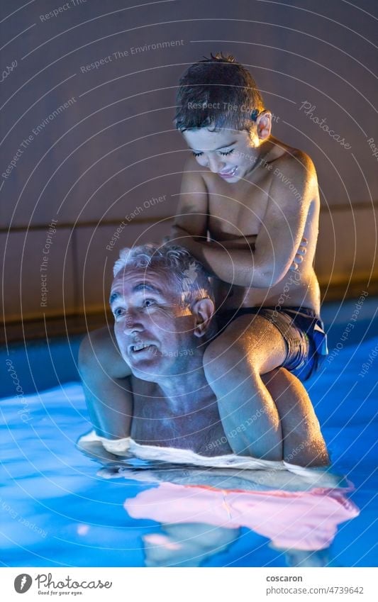 Grandfather and grandson  playing in a swimming pool at night active activity adult baby boy caucasian cheerful child childhood cute elderly enjoy evening