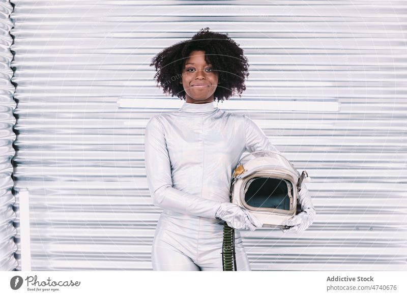Black woman in astronaut costume spacesuit smile helmet spaceship cosmonaut mission uniform content happy modern safety african american black light confident