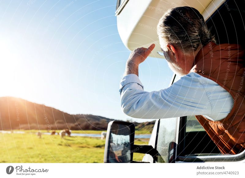 Faceless man looking out window of trailer in nature motorhome car rv camper field road trip journey caravan observe countryside transport parked male auto