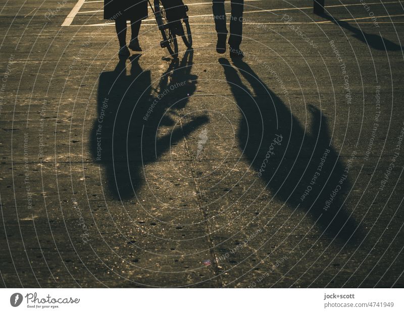Silhouette of people walking together and pushing a bike in sunshine Human being Shadow Sunlight Neutral Background Woman Man Lanes & trails Shadow play Bicycle