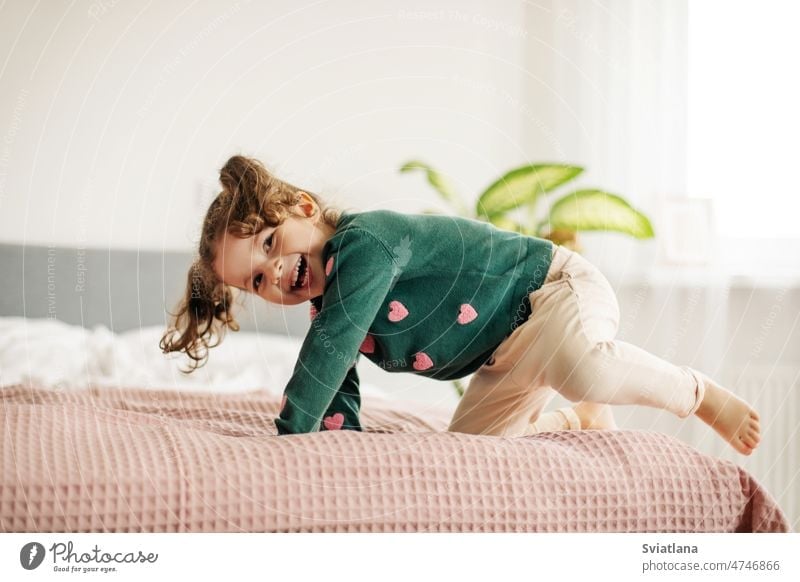 A cute little girl is lying on the bed with her leg raised and