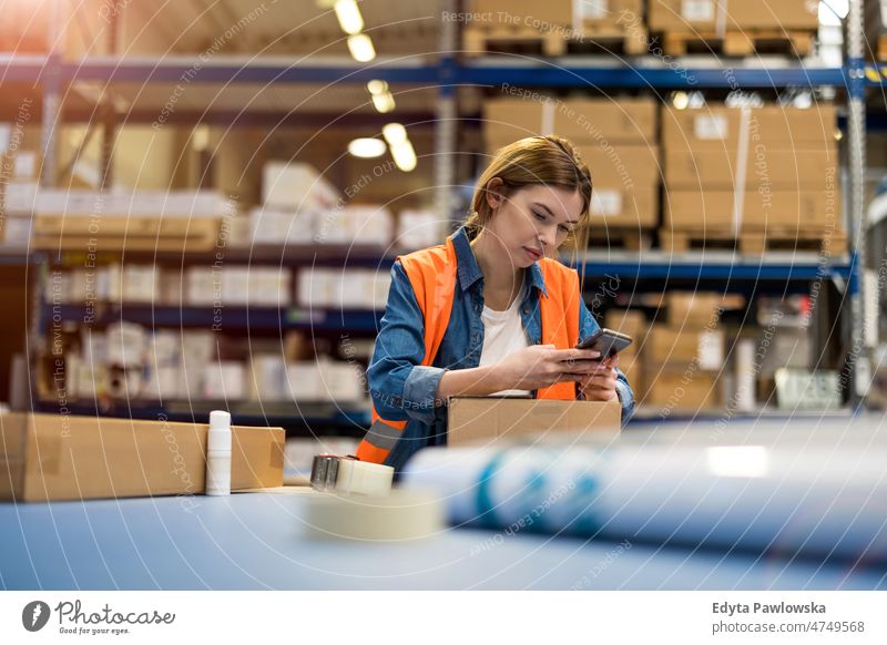 Female warehouse worker using mobile phone business cargo confident delivering delivery distribution employee factory female goods industrial industry job