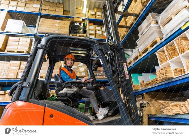 Young female forklift driver working in a warehouse business cargo confident delivering delivery distribution employee factory goods industrial industry job