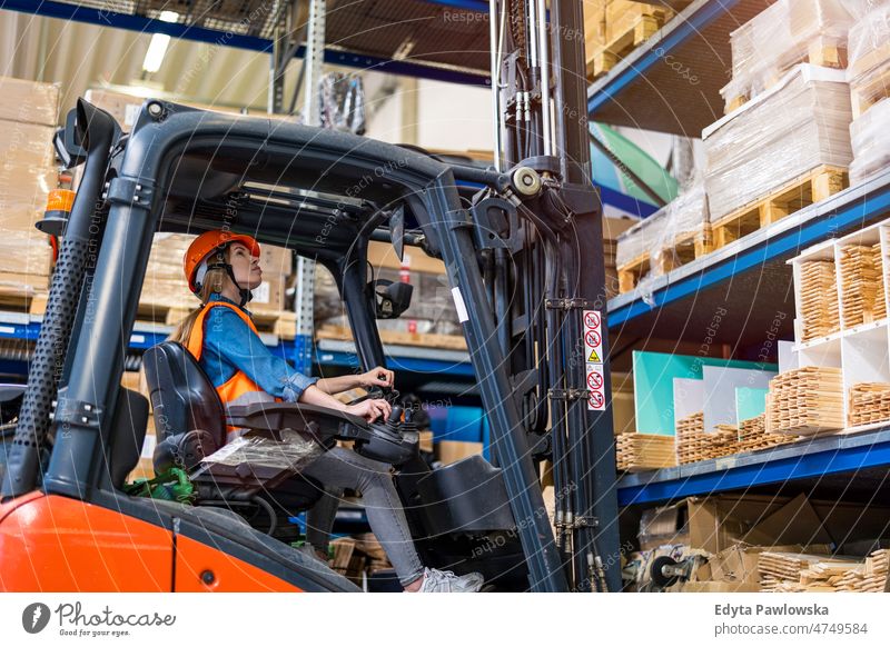 Young female forklift driver working in a warehouse business cargo confident delivering delivery distribution employee factory goods industrial industry job