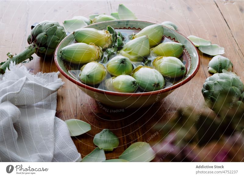 Bowl with peeled artichokes on wooden table fresh unpeeled water ripe bowl healthy food vegetarian cook kitchen culinary prepare raw ingredient recipe harvest