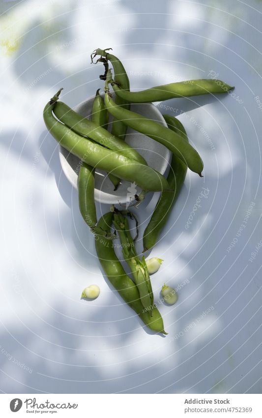 Bunch of green beans on table bowl sunlit fresh raw organic summer natural food ingredient vitamin nutrition vegetarian uncooked pea product sunlight shade