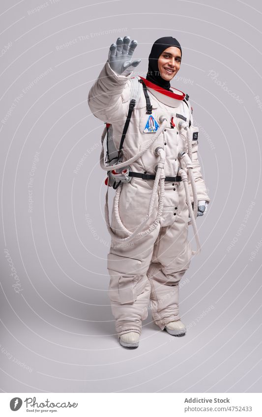 Smiling ethnic astronaut waving hand in camera man spacesuit goodbye mission ready wave hand explore astronomy discovery latin hispanic male gesture spaceman