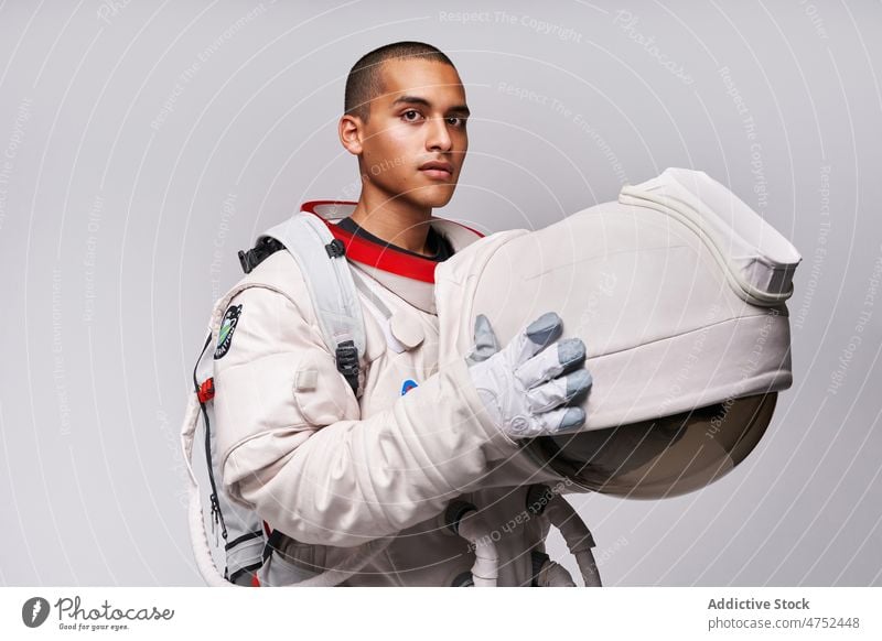 Astronaut taking off helmet of spacesuit in studio cosmonaut discovery courage concept model studio shot explore universe armor take off flight uniform latin