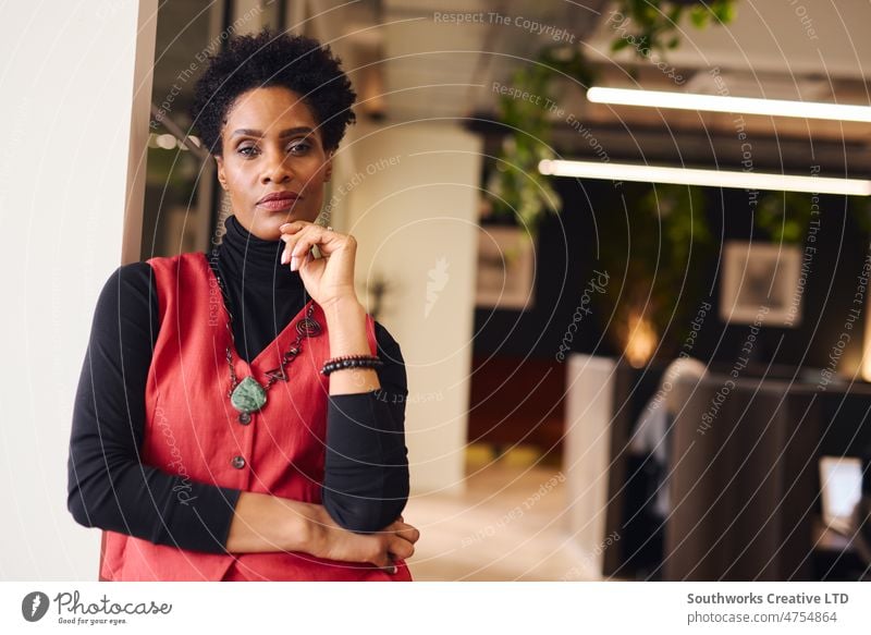 Portrait of mature black woman with hand on chin looking at camera with a pensive expression in coworking space businesswomen business owner portrait female