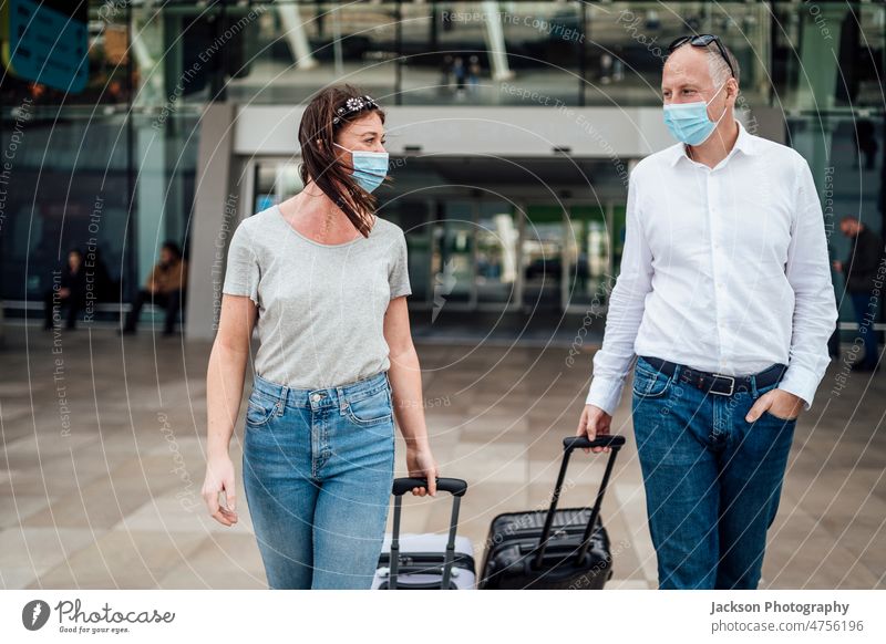 Travellers in protective masks chatting while leaving the airport with their luggage travel pandemic woman talk boy friends people couple traveller destination