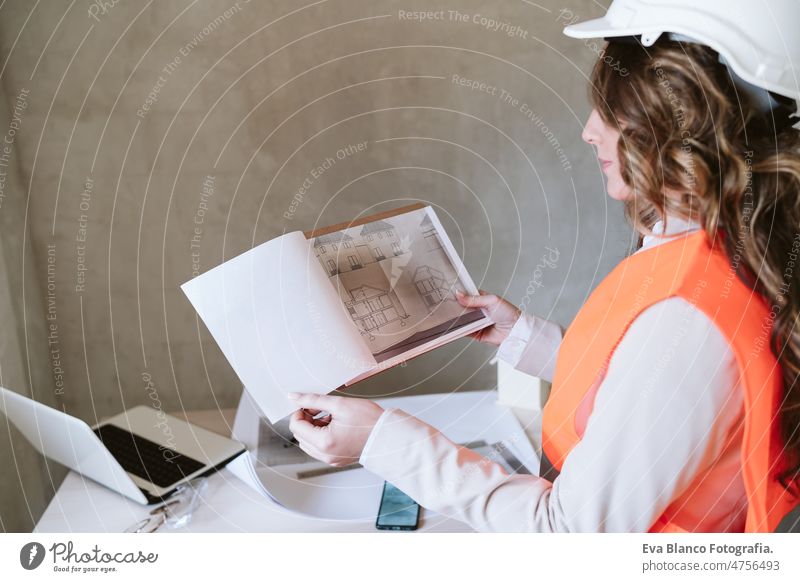 professional architect woman in construction site working on blueprints. Home renovation confident workspace protective helmet protective jacket real estate