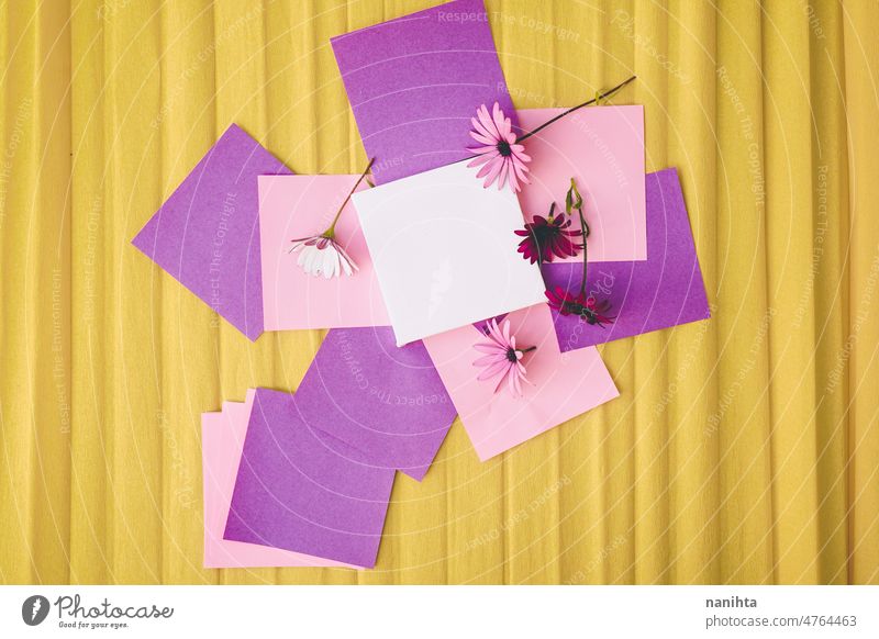 Mockup image with a white canvas surrounded by color papers and flowers mockup spring design colorful vibrant post-it sticky notes yellow purple pink tones