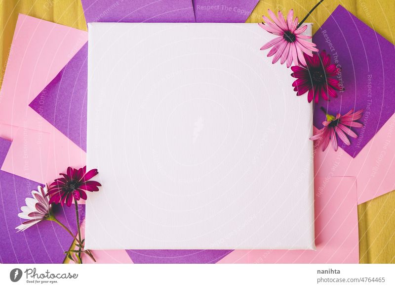 Mockup image with a white canvas surrounded by color papers and flowers mockup spring design colorful vibrant post-it sticky notes yellow purple pink tones