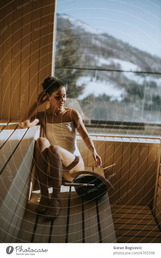Young Woman in Towel Relaxing on Bench in Sauna Stock Photo
