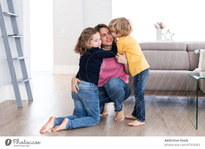 Children kissing mother in living room children sibling pastime spend time love childhood caress hug embrace motherhood bonding together childcare sofa daughter