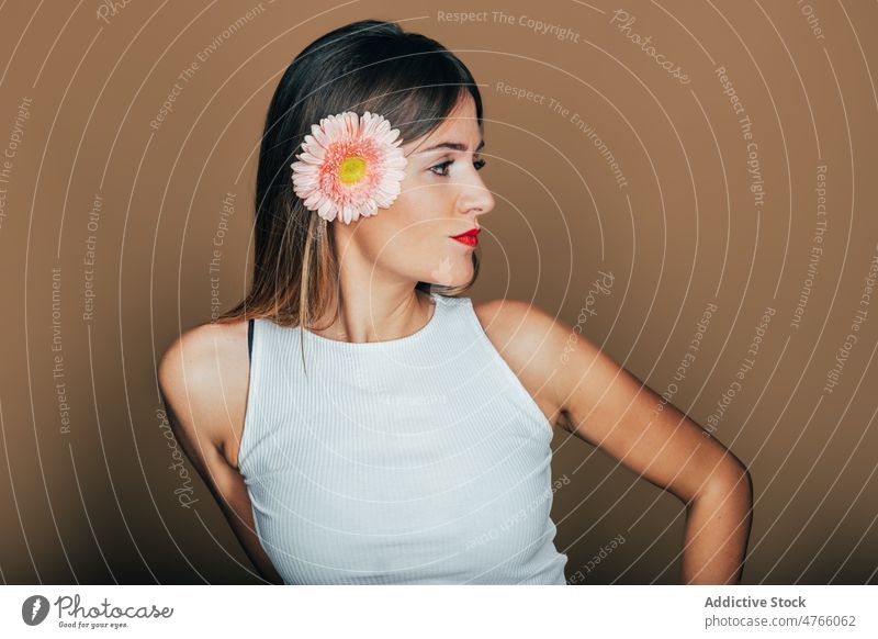 Confident woman with flower bloom in hair in studio model confident gerbera style self assured charismatic charming cool female appearance feminine serious