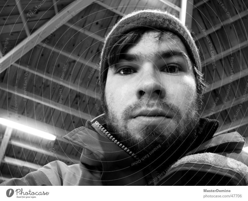 disorientation Portrait photograph Masculine Man Facial hair Lips Beard Cap Woolen hat Jacket Wooden roof Lamp Indifferent Amazed Surprise Unclear Interior shot