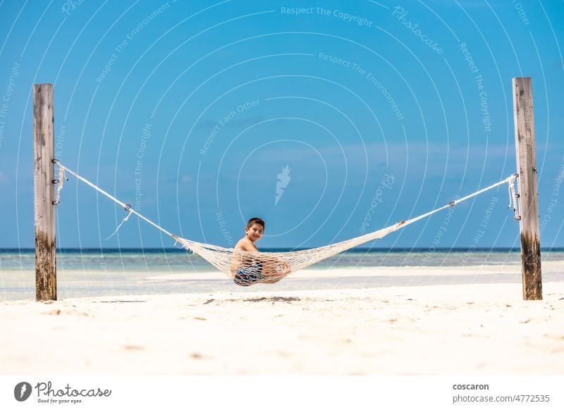 Little kid resting in a hammock on a white sand beach boy caucasian child childhood coast cute enjoyment fun happiness happy holiday island landscape leisure