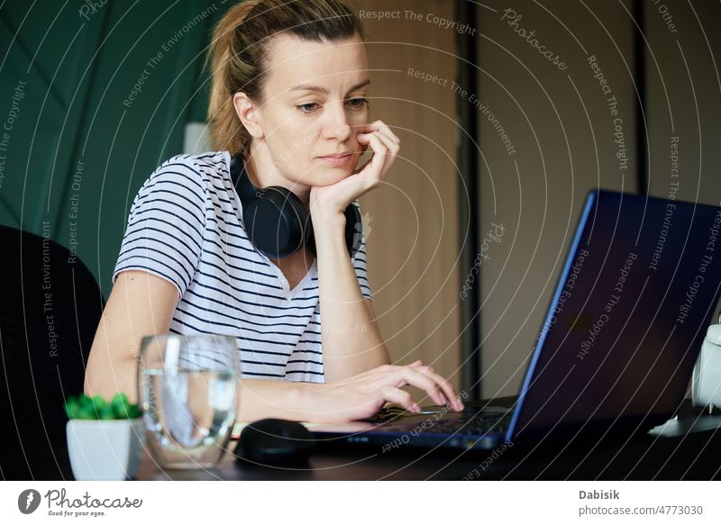 Woman working remotely at home office with laptop workplace freelancer business busy overwork table water glass plant woman computer girl interior lifestyle