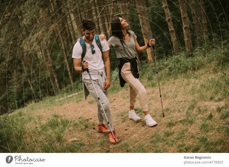 Couple of hikers with backpacks walk through the forest nature hiking activity trekking young woman freedom leaves girl lifestyle young man female adventure