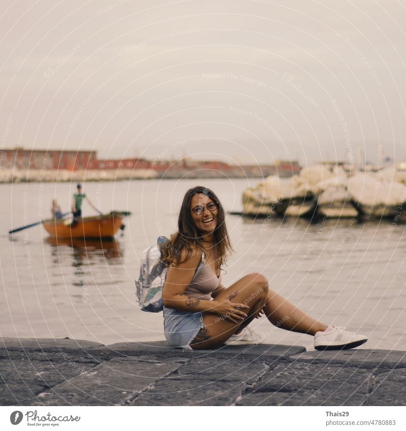 Young pretty woman sitting alone on the pier near the sea, smiling and laughing back background beach beautiful calm city evening female freedom girl landscape