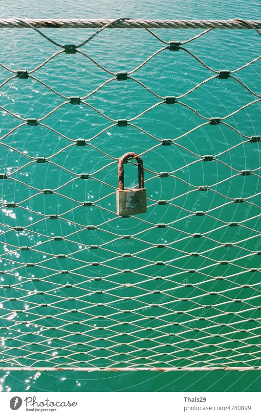 love lock hanging from a fence in front of the sea. padlock attached to the fence in front sea beauty aqua calm vacation landscape blue outdoor wave ocean water