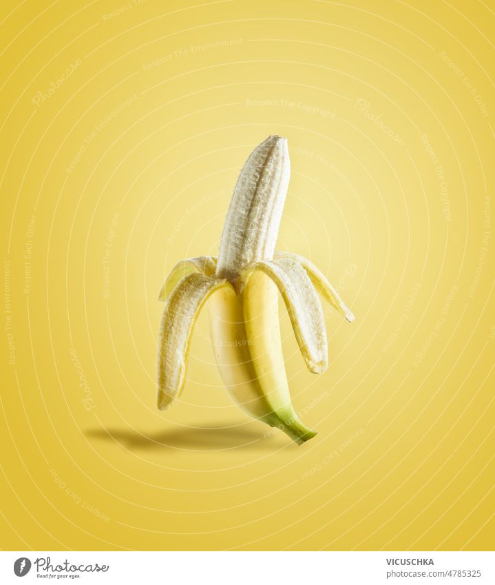 Half peeled banana in sunlight on yellow background half delicious tropical fruit front view food fresh half peeled healthy isolated nutrition raw ripe summer