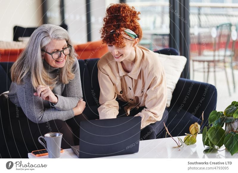 Portrait of two white businesswomen using laptop and smiling, senior woman with glasses and young woman with red hair portrait businesswoman adult teamwork