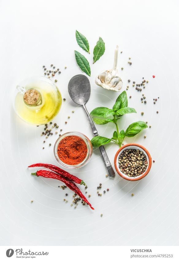 Healthy ingredients for food flavoring: olive oil, basil leaves, chili, garlic, pepper, bay leaves and spoon on white background healthy cooking preparation