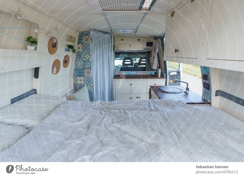 bright white and brown interior of homemade camper van with bed, wardrobe and sink Mobile home travel Caravan Camping voyage Lifestyle inward Van Vehicle