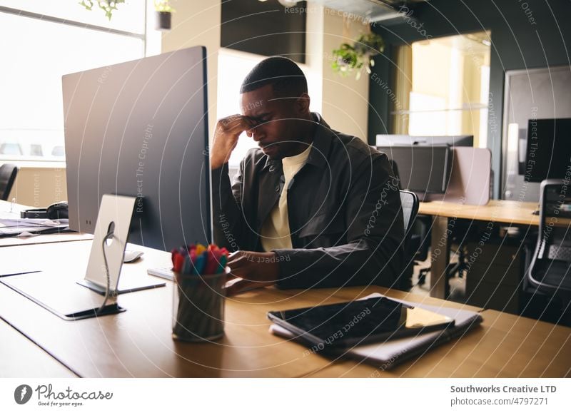 Stressed black businessman sat at office desk with mental illness mental health stressed Mental burnout depressed Male 30's mid adult African american workload