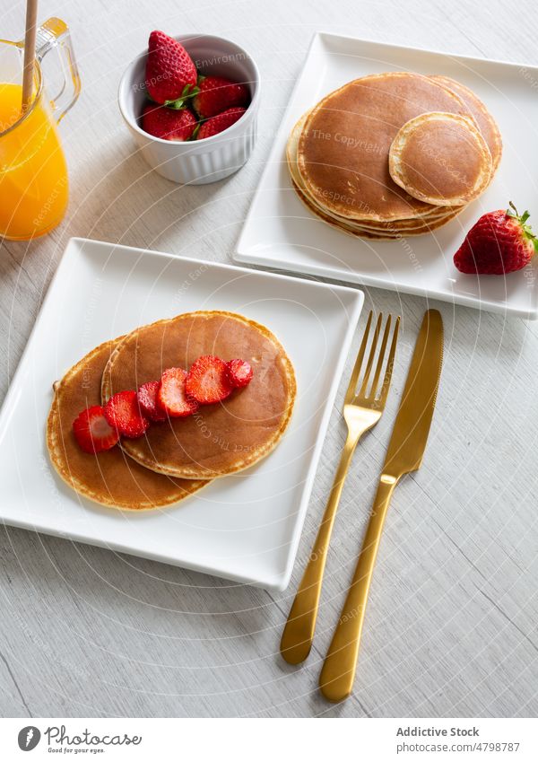 Pancakes with strawberries near juice pancake dessert strawberry breakfast sweet serve kitchen food morning delectable delicious fresh orange plate tasty