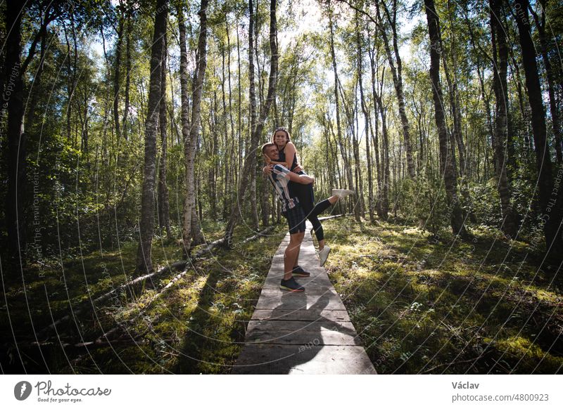 Couple in love hugging on duckboards in the middle of the Finnish wilderness. The joy of discovering Scandinavia. A girl looks down on her boyfriend. Real feelings in real life